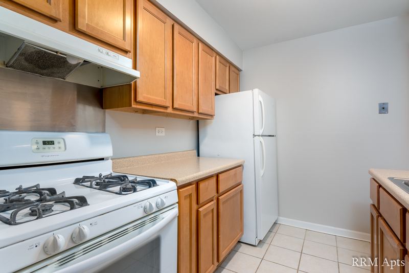 Kitchen with oak cabinets, white gas stove, refrigerator and tile floor, 4th and Broadway apartment 1A