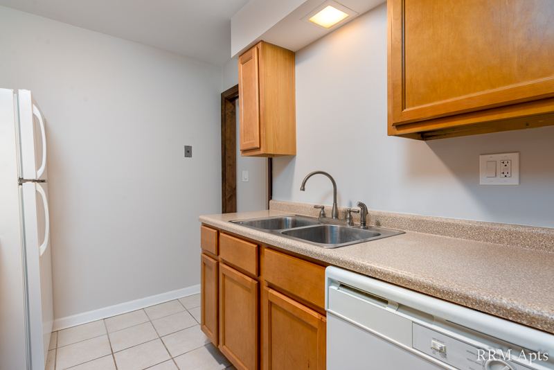 Kitchen with oak cabinets, double sink, dishwasher and tile floor, 4th and Broadway apartment 1A