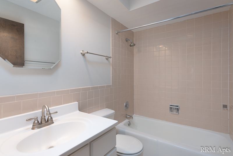 Bathroom with white vanity, tiled tub and shower, 4th and Broadway apartment 1A