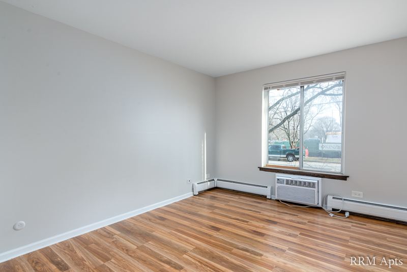 Bedroom with window, wall air conditioner and hardwood floor, 4th and Broadway apartment 1A