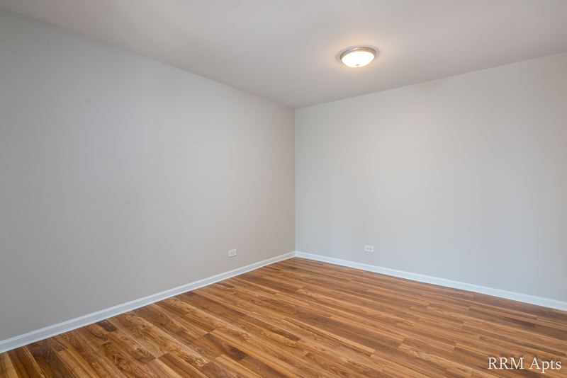 Empty room with wood floor, gray walls, ceiling light and baseboard radiator, 4th and Broadway apartment 1B