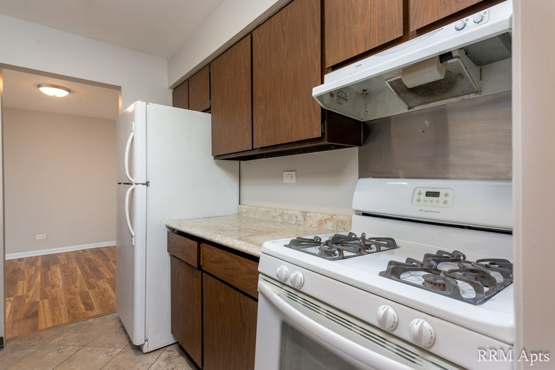 Kitchen with white gas stove, white refrigerator, dark wood cabinets and wood floor, 4th and Broadway apartment 1B