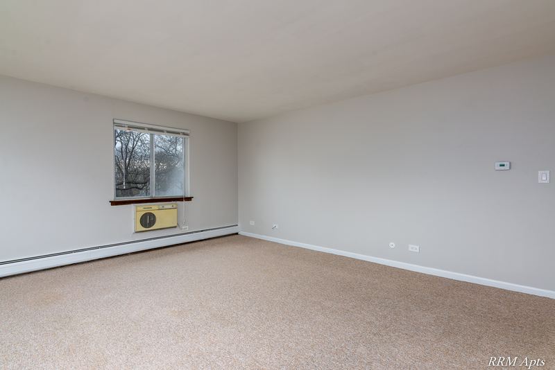Carpeted bedroom with one window, wall air conditioner and baseboard radiator, 4th and Broadway apartment 2A