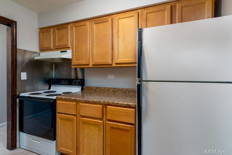 Kitchen with oak cabinets, white electric stove, white refrigerator and granite-look counter, 4th and Broadway apartment 2A