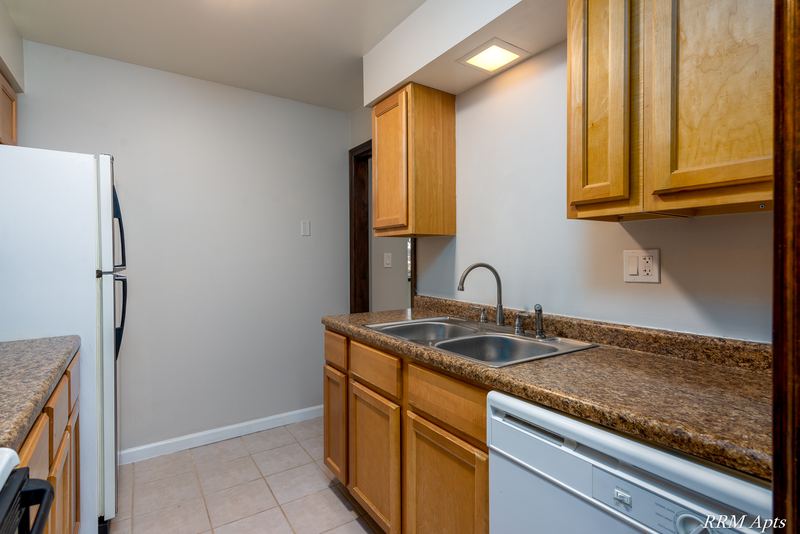 Kitchen with oak cabinets, stainless sink, white dishwasher and granite-look counter, 4th and Broadway apartment 2A