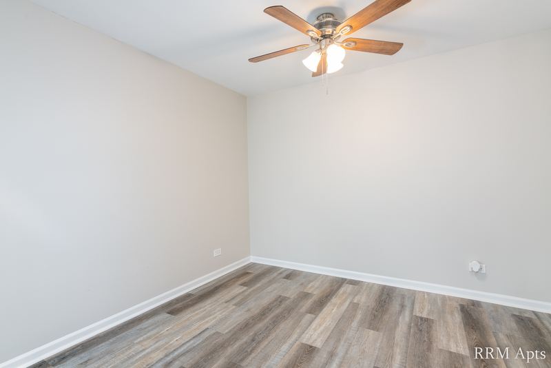 Bedroom with gray wood-look floor, ceiling fan and baseboard radiator, 4th and Broadway apartment 2B