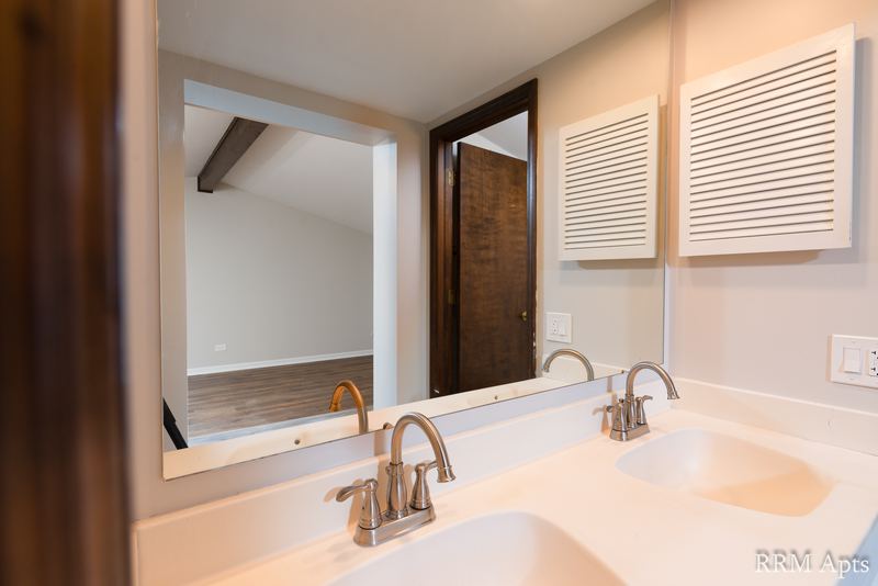 Bathroom with double-sink white vanity, chrome faucets and a wide mirror, 4th and Broadway apartment 2C