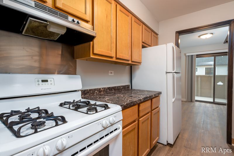 Kitchen with white gas stove, white refrigerator, oak cabinets and sliding glass door beyond, 4th and Broadway apartment 2C