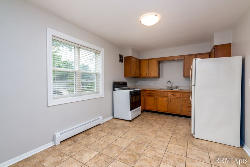 Kitchen with oak cabinets, white stove, white refrigerator, tile floor and one window, Austin Avenue apartment 116 A