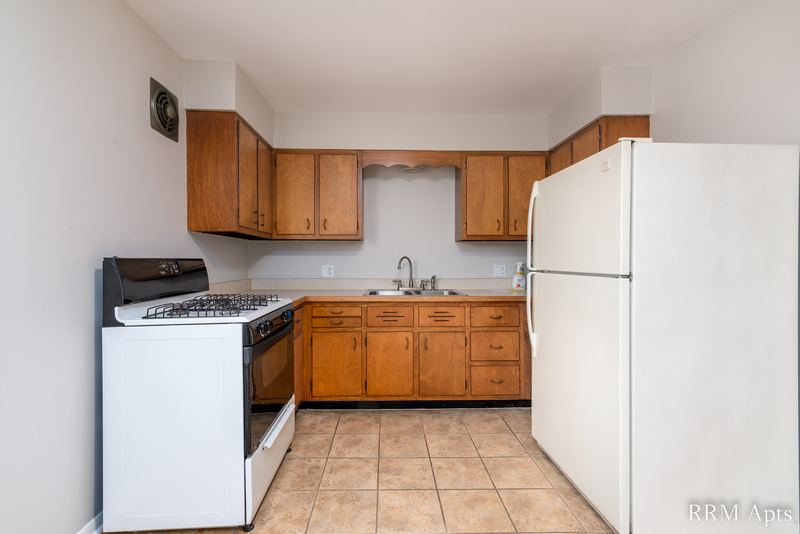 Kitchen with white gas stove, oak cabinets, white refrigerator and tile floor, Austin Avenue apartment 116 A