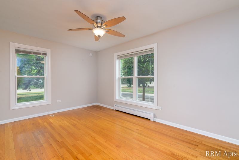 Bedroom with wood floor, two windows, ceiling fan and baseboard radiator, Austin Avenue apartment 116 A