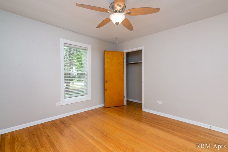 Bedroom with wood floor, ceiling fan, a window and a wood door beside the closet, Austin Avenue apartment 116 A