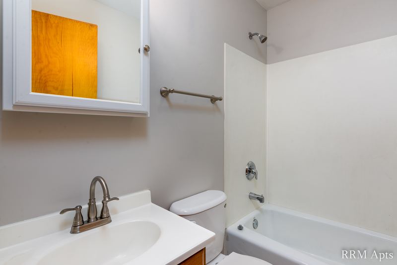 Bathroom with white tub and surround, white vanity sink and a wood medicine cabinet, Austin Avenue apartment 116 A