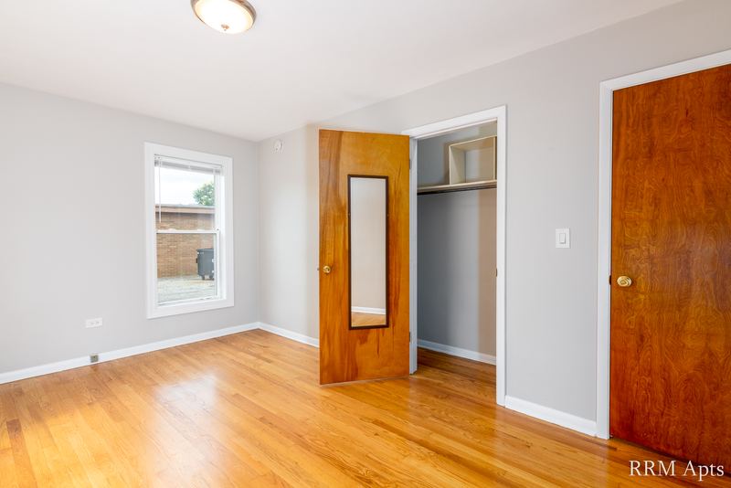 Bedroom with wood floor, one window, an open closet and two wood doors, Austin Avenue apartment 118 A