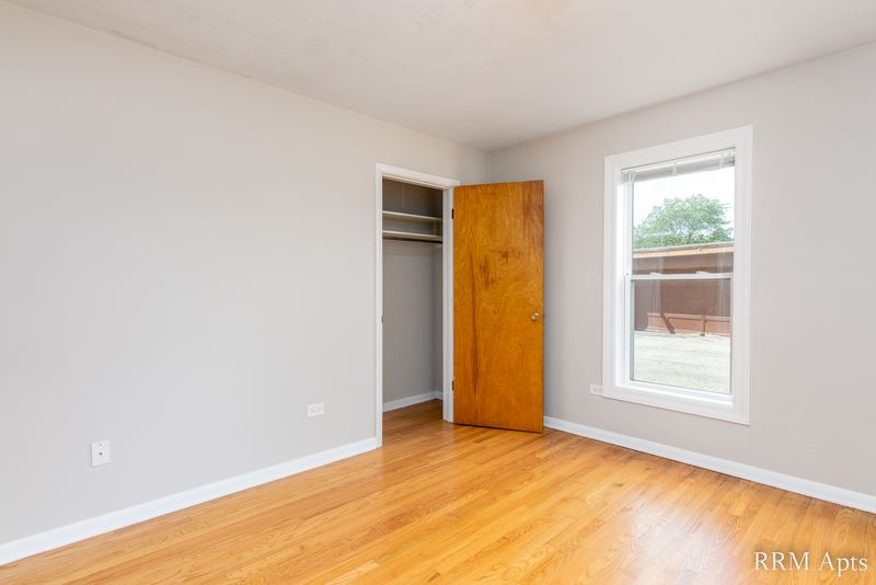 Bedroom with wood floor, one window and an open closet with wood door, Austin Avenue apartment 118 A