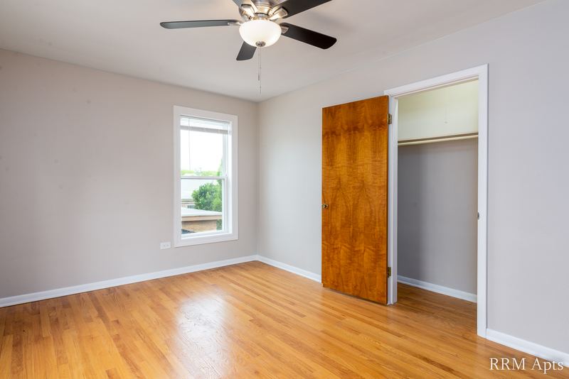 Bedroom with wood floor, ceiling fan, one window and an open closet with wood door, Austin Avenue apartment 118B