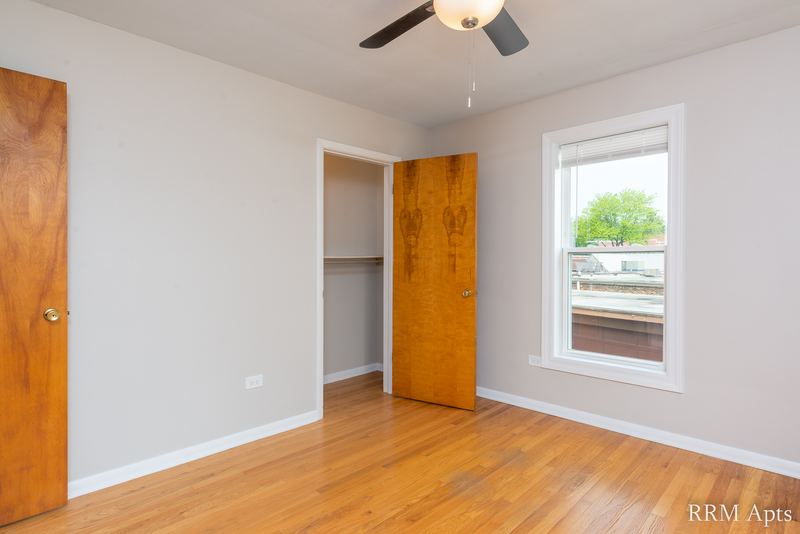 Bedroom with wood floor, ceiling fan, two wood doors, an open closet and one window, Austin Avenue apartment 118B
