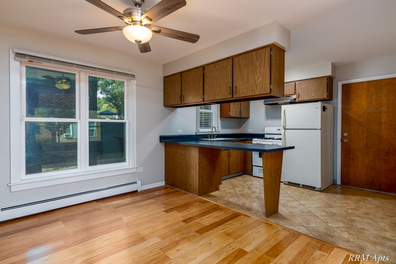 Kitchen with dark wood cabinets, dark counter, white refrigerator and stove, and a ceiling fan, Austin Avenue apartment 120 A