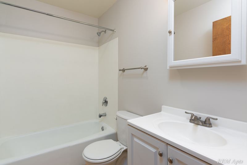 Bathroom with white tub and surround, toilet, white vanity and a medicine cabinet, Austin Avenue apartment 120 A