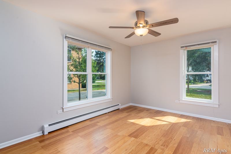 Bedroom with wood floor, ceiling fan and two windows looking out at trees, Austin Avenue apartment 120 A