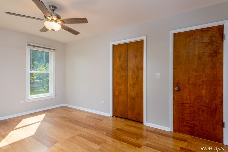 Bedroom with wood floor, ceiling fan, one window and two wood doors, Austin Avenue apartment 120 A