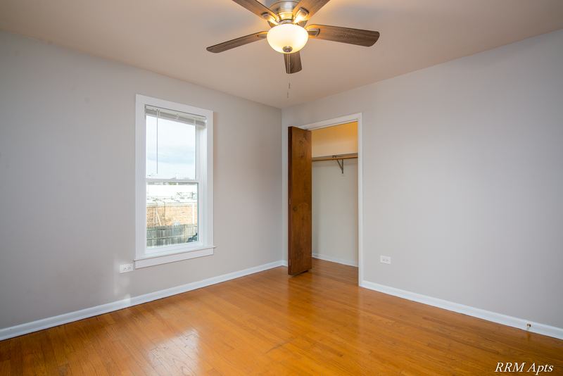 Bedroom with wood floor, ceiling fan, one window and an open closet on the right, Austin Avenue apartment 122 B