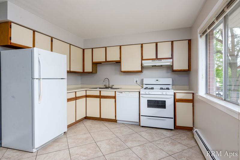 Kitchen with white refrigerator, white stove, wood-trimmed white cabinets, tile floor and a window, Cook Street apartment 4
