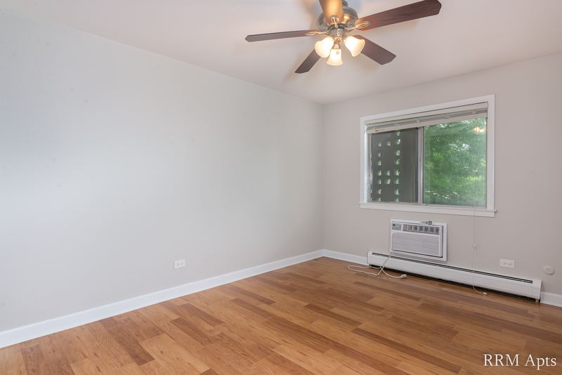 Bedroom with wood floor, ceiling fan, one window with a wall air conditioner below it, Cook Street apartment 4