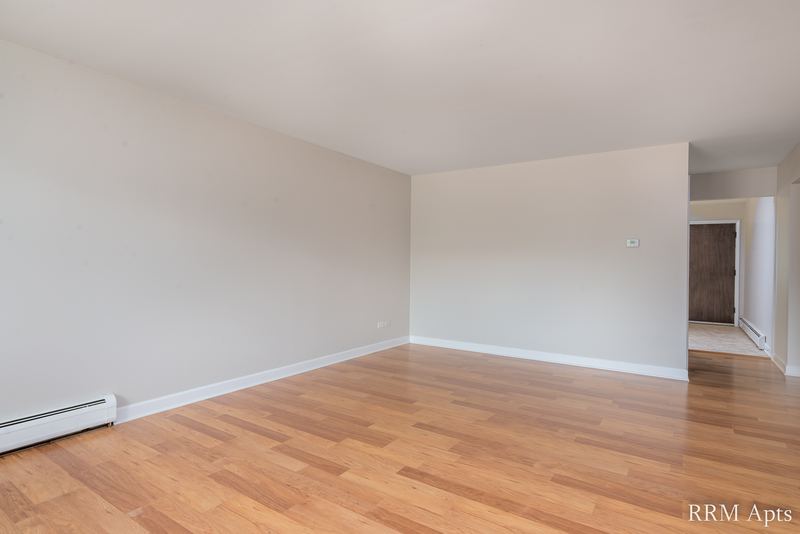Empty room with wood floor, baseboard radiator and a wide opening to the next room, Cook Street apartment 4