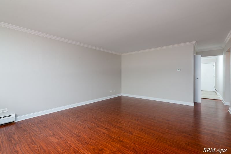 Living and dining area with wood-look floor and crown molding, Cook Street apartment 6