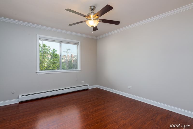 Bedroom with ceiling fan, window, baseboard heater and wood-look floor, Cook Street apartment 6