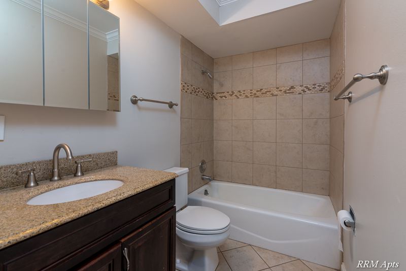 Bathroom with granite vanity, mirrored cabinet and tiled tub with mosaic accent, Cook Street apartment 6