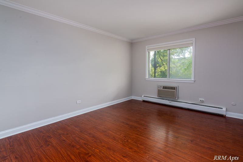 Bedroom with window, wall air conditioner, baseboard heater and wood-look floor, Cook Street apartment 6