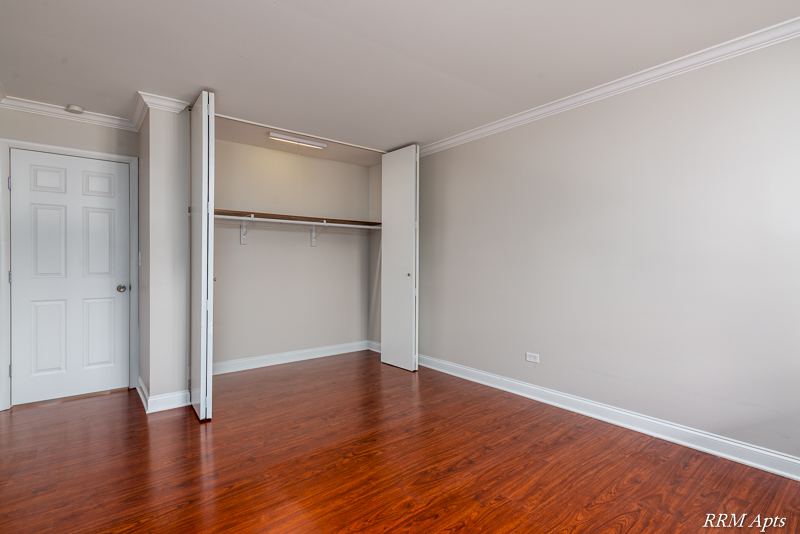 Bedroom with open closet, door and wood-look floor, Cook Street apartment 6