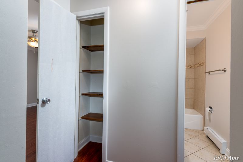 Hallway linen closet with wood shelves next to the bathroom, Cook Street apartment 6