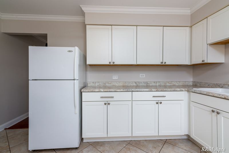 Kitchen with white cabinets, white refrigerator and granite-look counter, Cook Street apartment 6