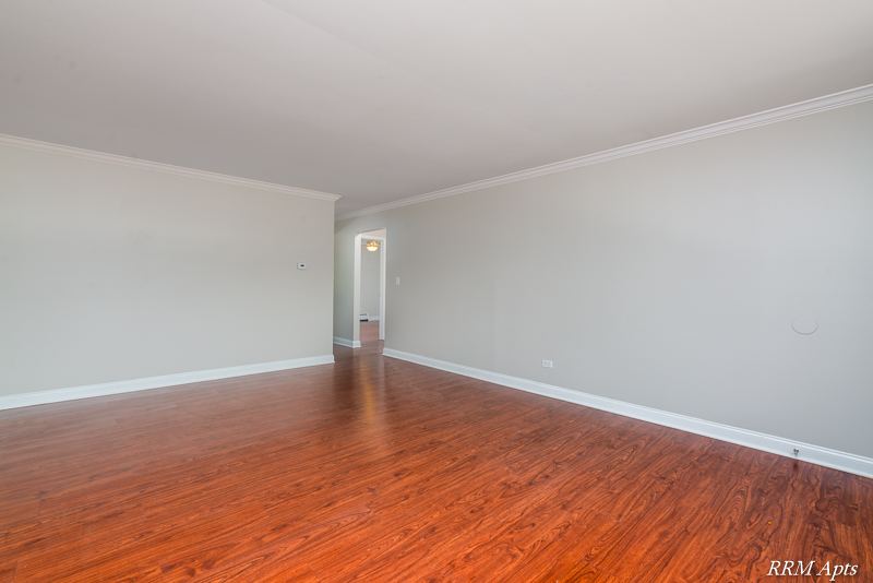 Living room with wood-look floor and crown molding leading to the hallway, Cook Street apartment 6