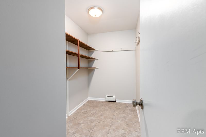 Closet with wood shelving and rod, tile floor, ceiling light and baseboard radiator, Cook Street apartment 9