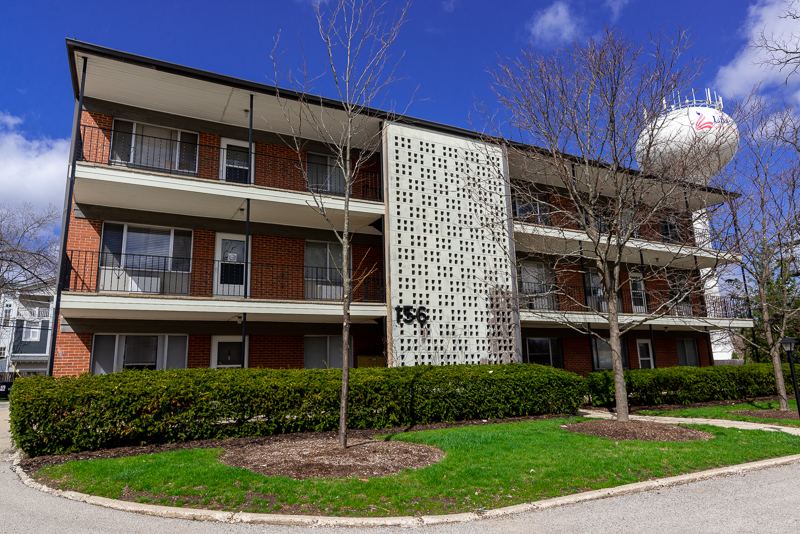 Three-story brick apartment building with balconies and a decorative block screen wall at Cook Street, Libertyville