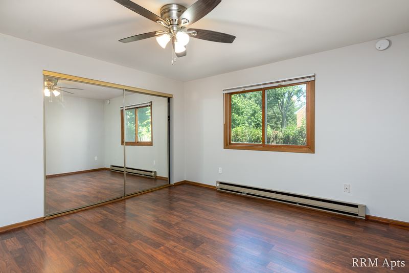 Bedroom with wood floor, ceiling fan, mirrored sliding closet doors and one window, Depot Road apartment 1