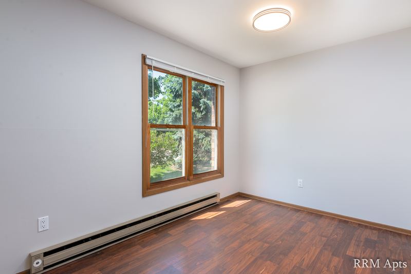Bedroom with wood floor, one wood-trimmed window, baseboard radiator and a ceiling light, Depot Road apartment 1