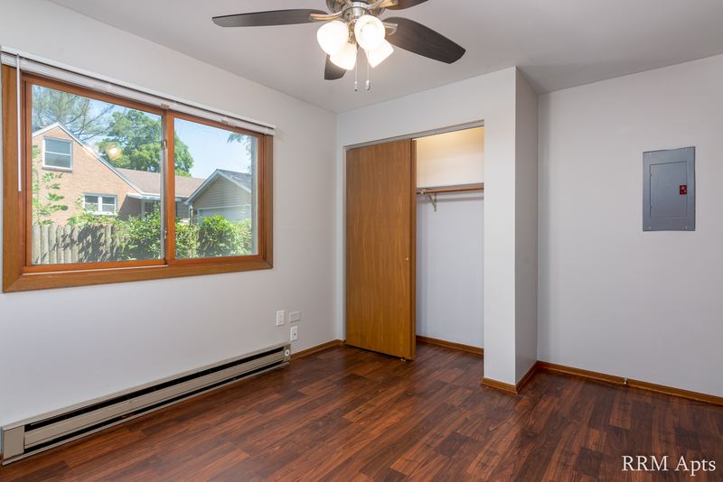 Bedroom with wood floor, ceiling fan, a window looking at a house, open closet and electrical panel, Depot Road apartment 1