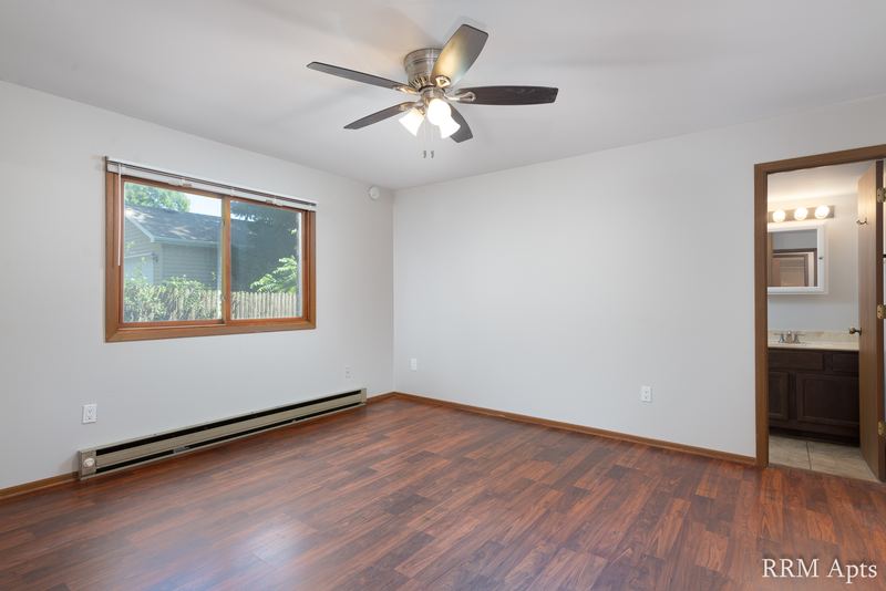 Bedroom with wood floor, ceiling fan, one window, baseboard radiator and a doorway to the bathroom, Depot Road apartment 1