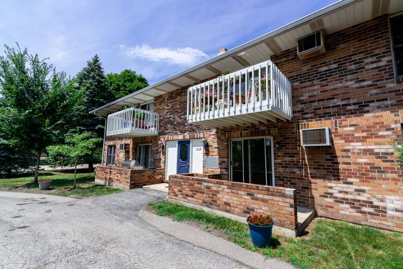 Building exterior with brick facade, white balcony railings, wall air conditioners and lawn, Depot Road apartment 2
