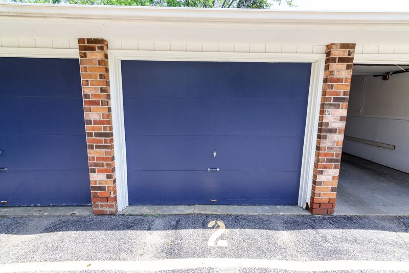 Garage with blue overhead door between brick pillars and the number 2 painted on the apron, Depot Road apartment 2