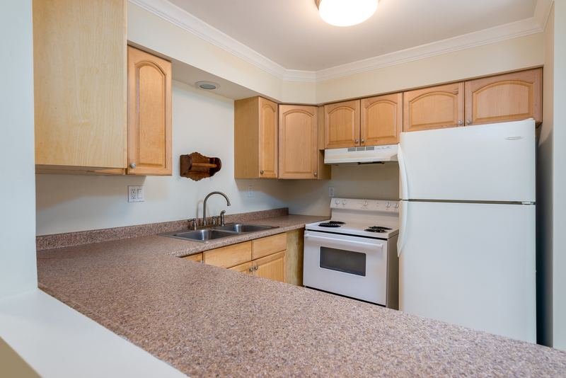 Kitchen with light oak cabinets, white refrigerator, white stove and a peninsula counter, Depot Road apartment 2