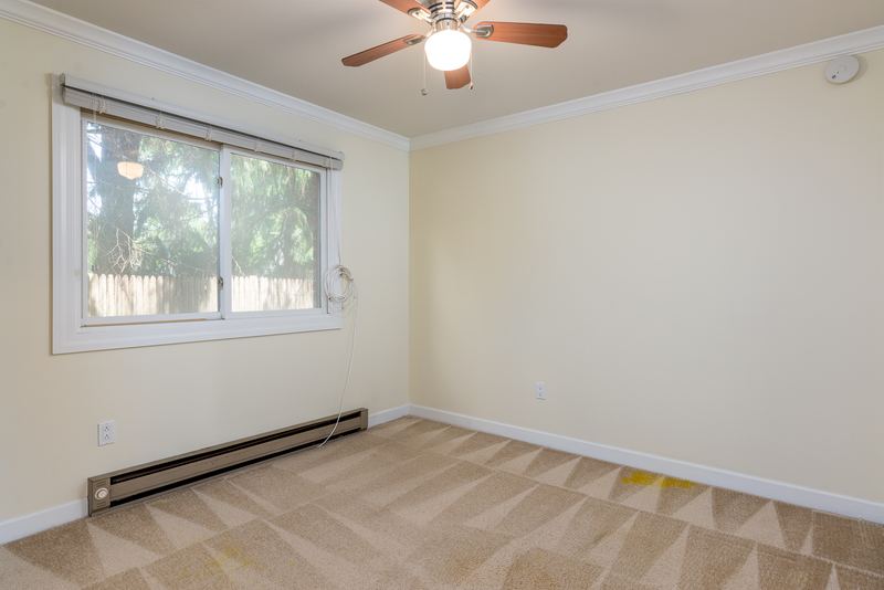 Carpeted bedroom with ceiling fan, one wide window and baseboard radiator, Depot Road apartment 2