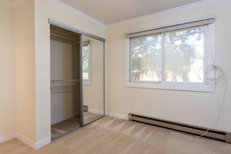 Carpeted bedroom with mirrored sliding closet doors, one window and baseboard radiator, Depot Road apartment 2