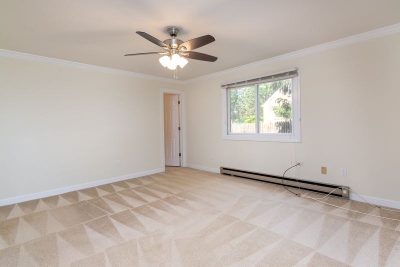 Carpeted bedroom with ceiling fan, one window, baseboard radiator and an open doorway, Depot Road apartment 2