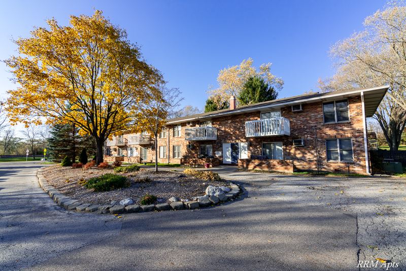 Two-story brick apartment building with balconies, a circular drive and autumn trees at Depot Road